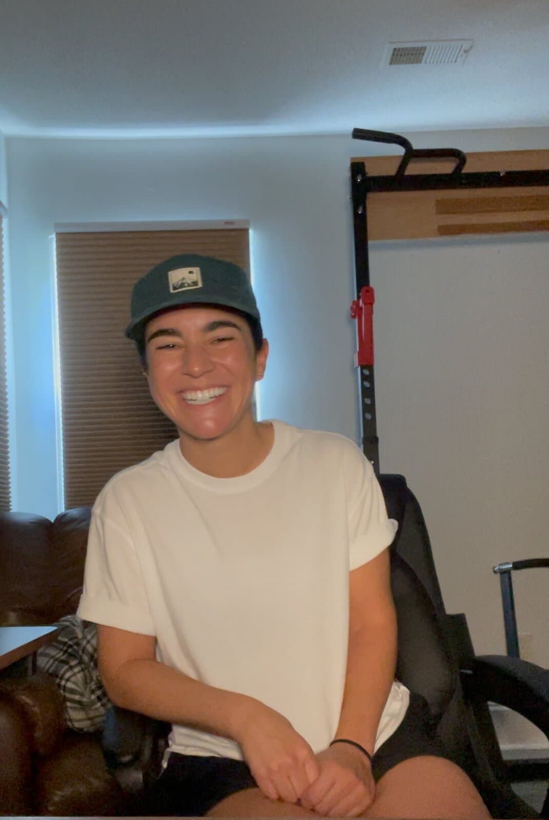 A contestant in a cap and white T-shirt smiling at the camera