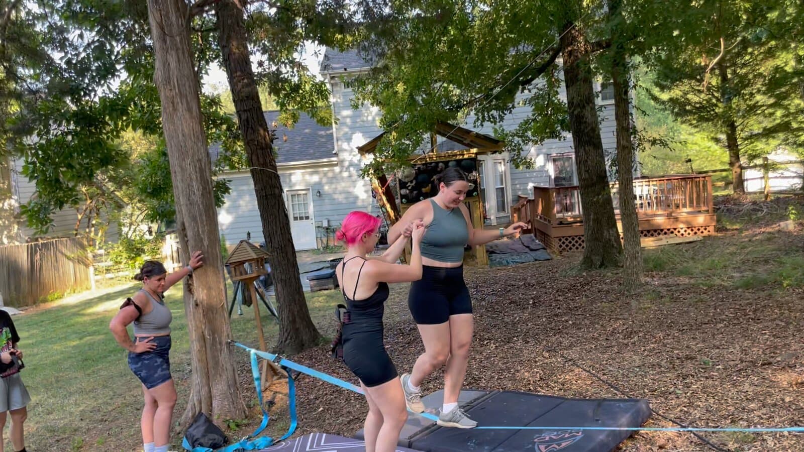 Two contestants helping each other across a slackline over crash pads